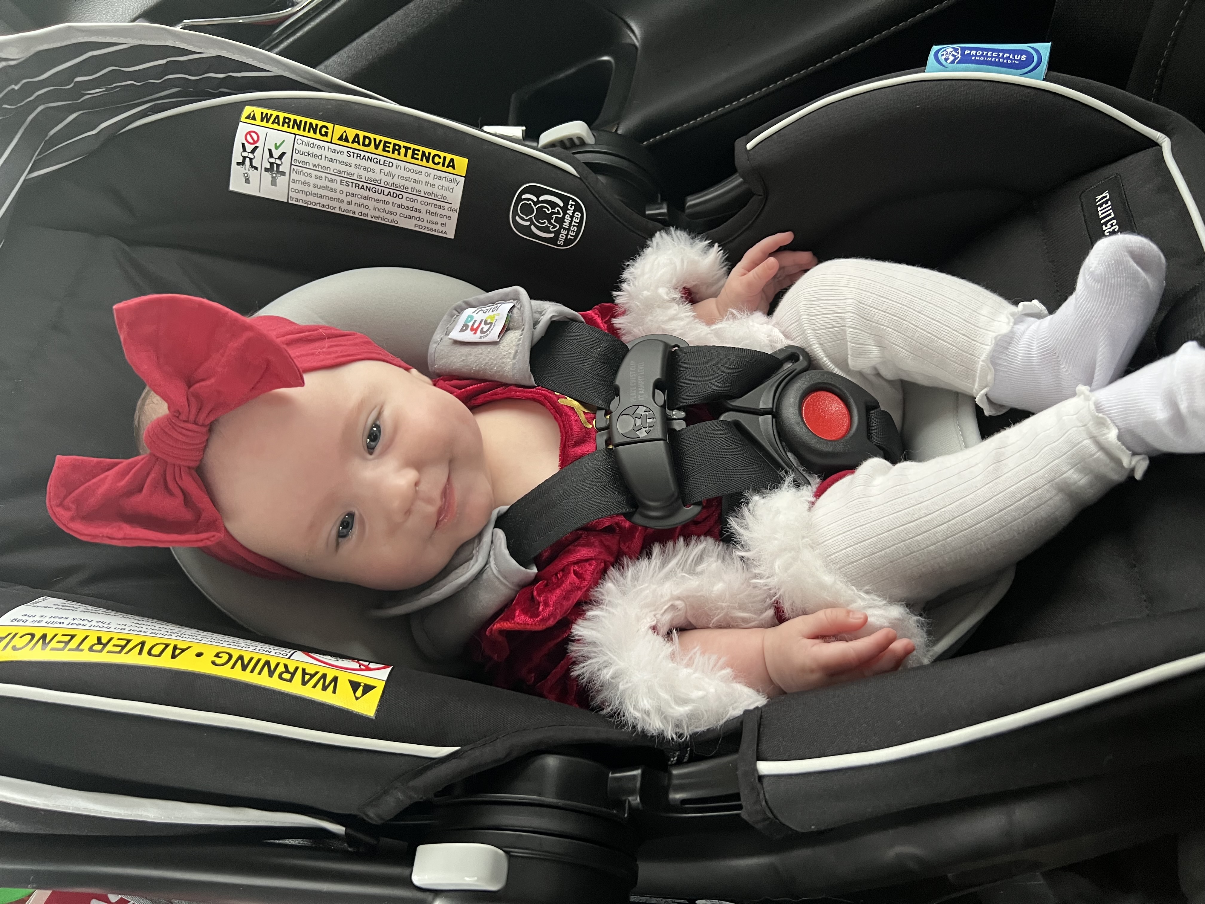 Baby Delilah in her car seat wearing a red and white outfit, ready for adventure